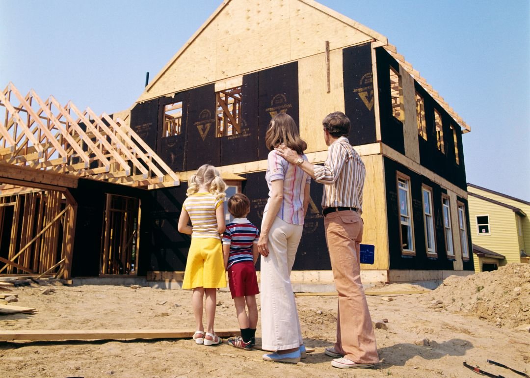 70’s era photo of a family standing in front of a new home being constructed - H. Armstrong Roberts/ClassicStock // Getty Images