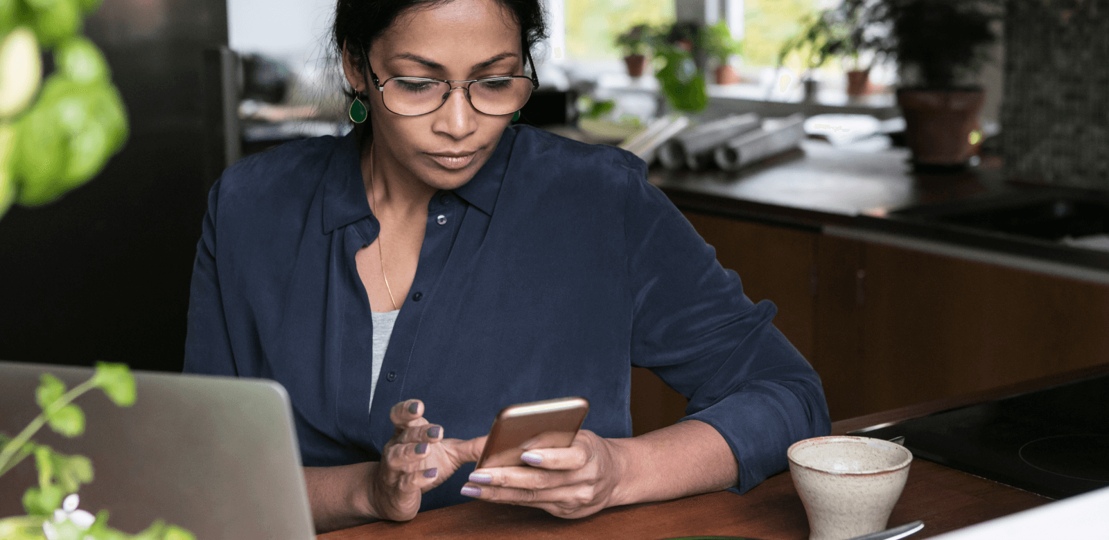 Person Interacting with a Cell Phone Sitting at Desk with a Laptop Computer