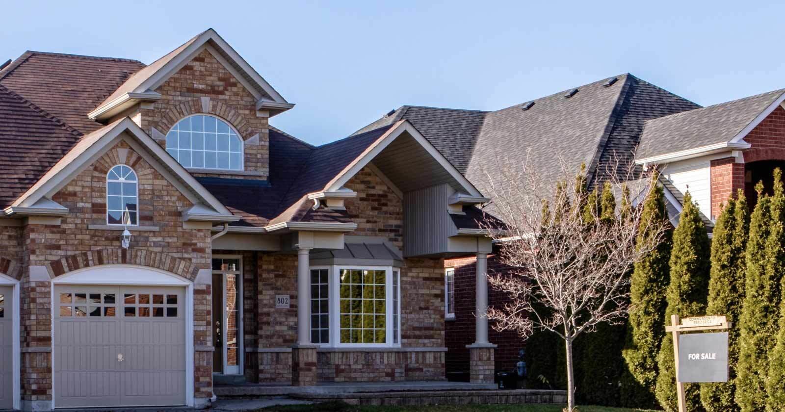 Large Suburban Brick Home with For Sale Sign Out Front