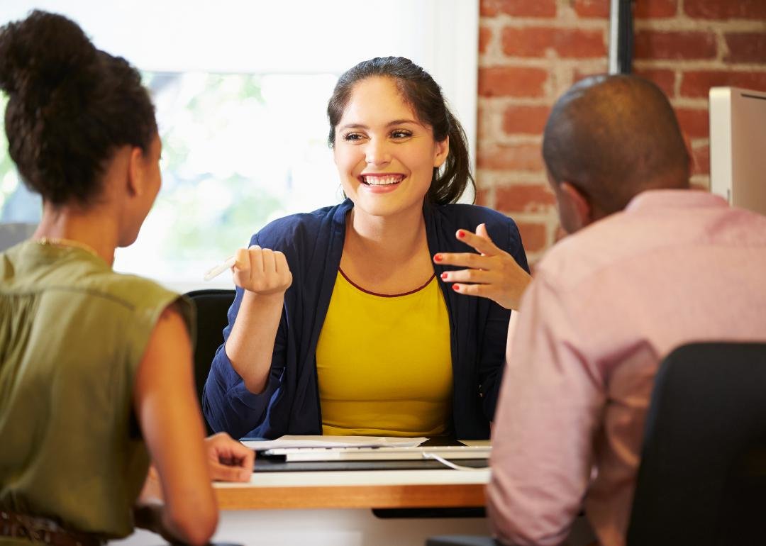 “Photograph of a couple in a conversation with a smiling lending agent” - Source: Canva