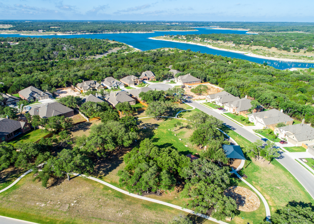 “Aerial photograph of a small neighborhood built in a forested area adjacent to a lake” -Source: Canva