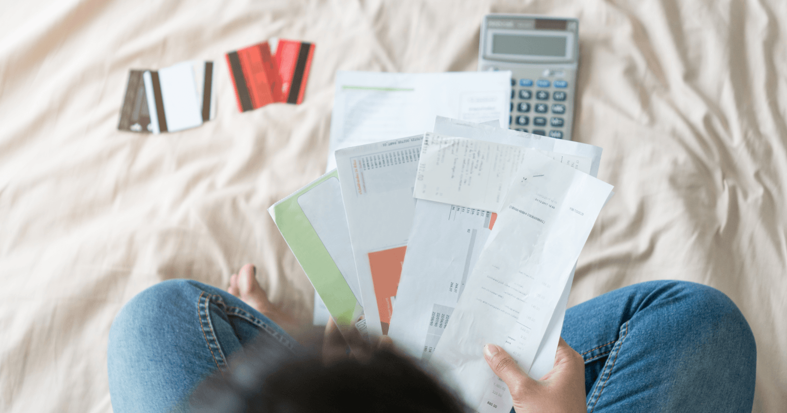 Top Down View of Person Reviewing Financial Documents on a Bed