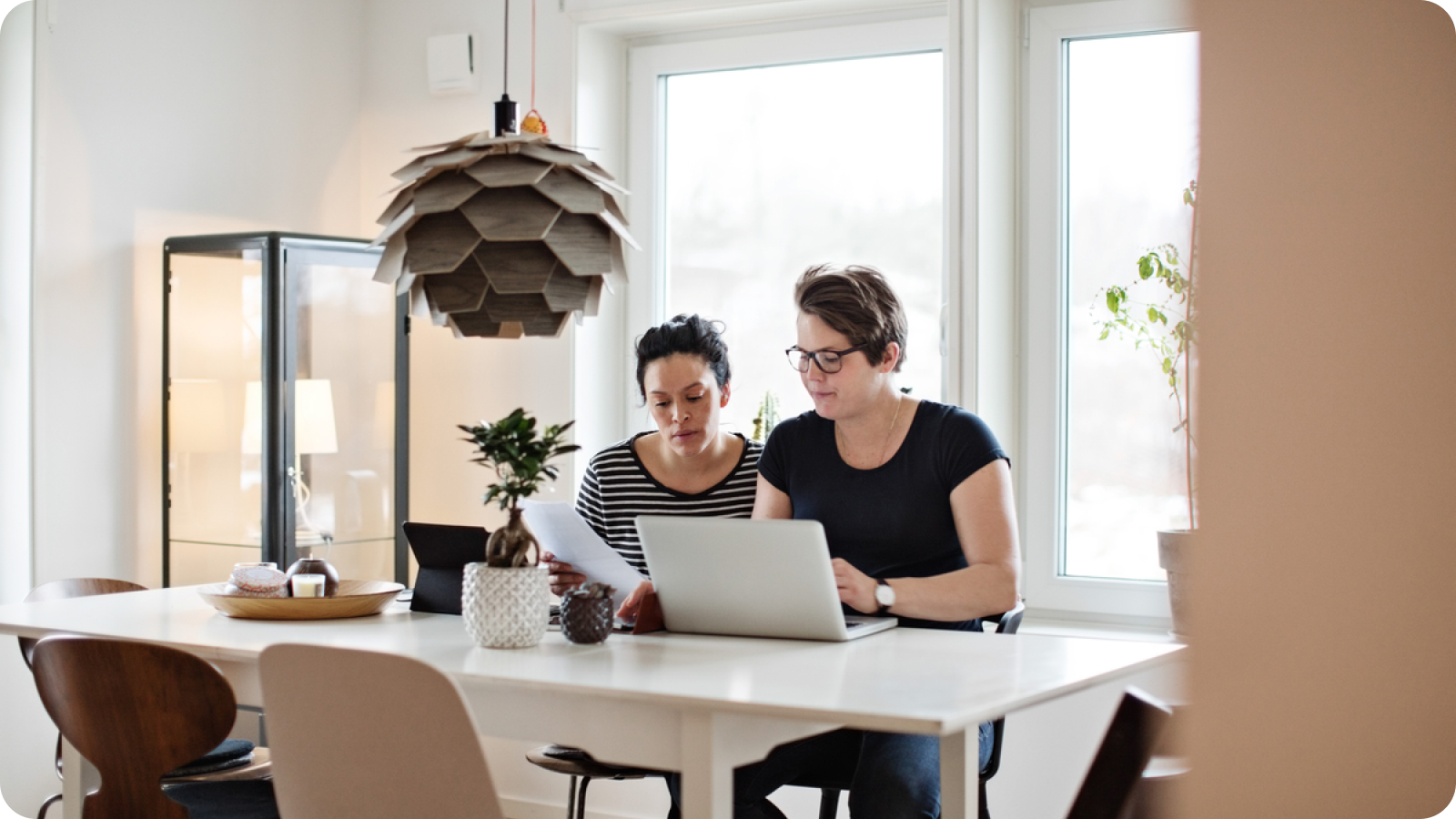 Two people reviewing information on a laptop and a piece of paper, learning how to get a mortgage approval.