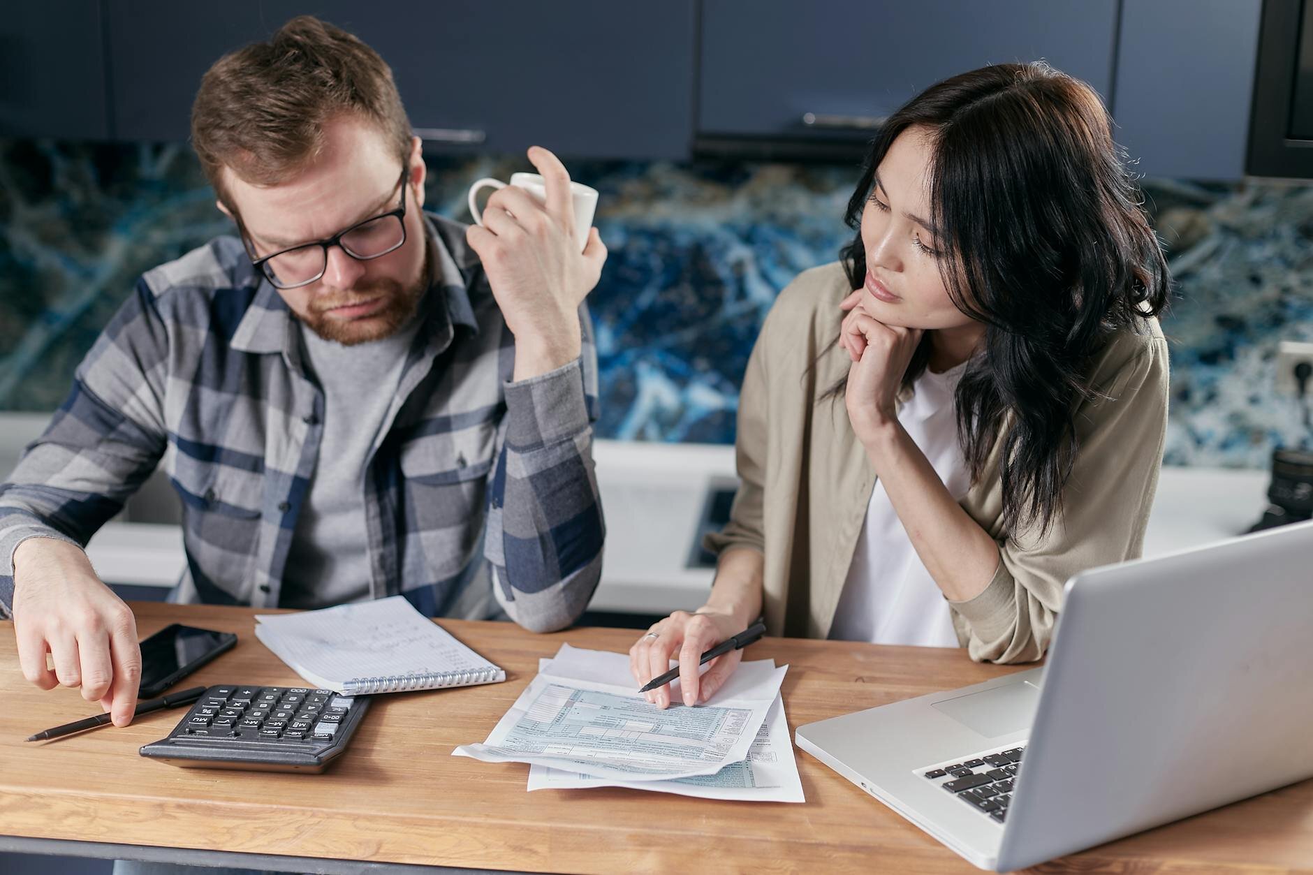 Smiling older couple managing finances with a laptop and phone at home.