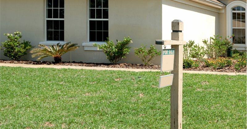 For Sale Sign in Front of House on Sunny Day