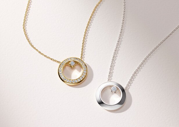 Gold tone Ono necklace with lab grown diamonds next to a silver Ono necklace with one lab grown diamond. 
