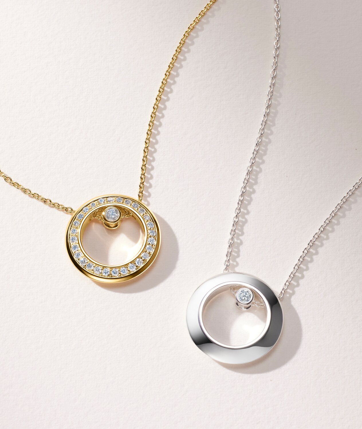 Women's Ono necklace in 18k gold vermeil with lab grown diamonds is laying next to the sterling silver Ono necklace with one lab grown diamond.