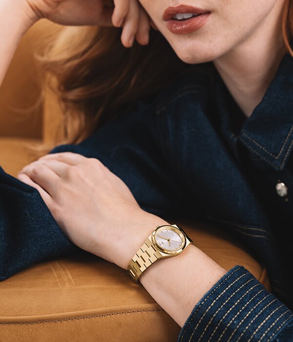 Woman in a denim shirt wearing the gold tone Movado BOLD Quest Mini Watch.