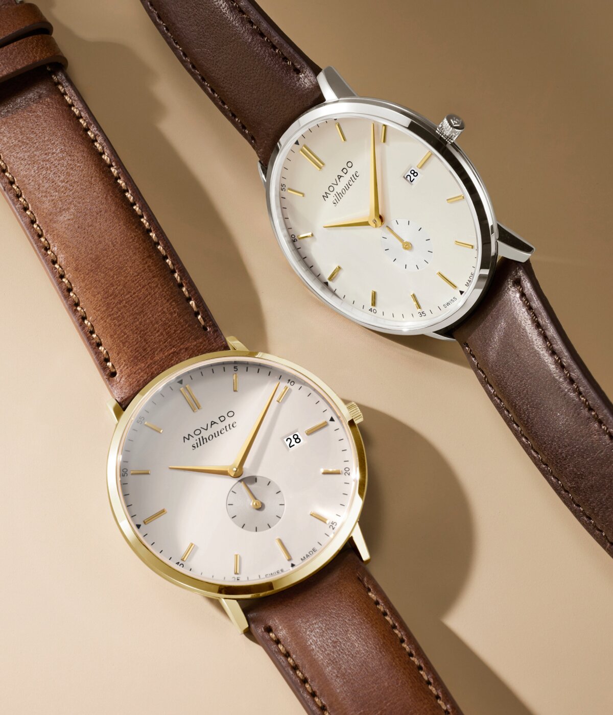 Two Heritage Series Silhouette watches laying next to each other. Both have a brown strap and white dial with gold tone accents.