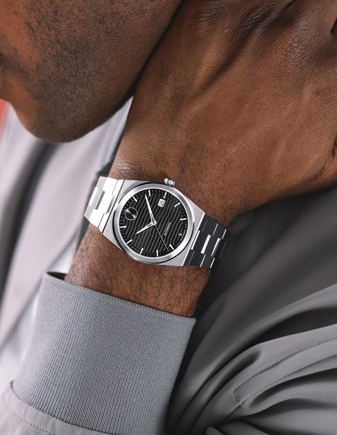 Man in a grey jacket wearing the BOLD Quest automatic watch with stainless steel bracelet and black dial.