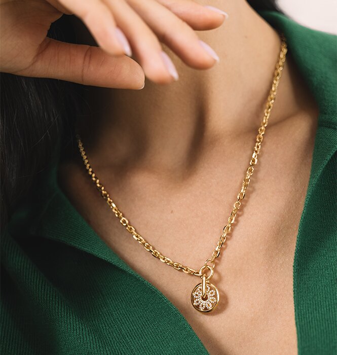 Woman in a green shirt wearing the gold tone fleur necklace featuring lab grown diamonds.