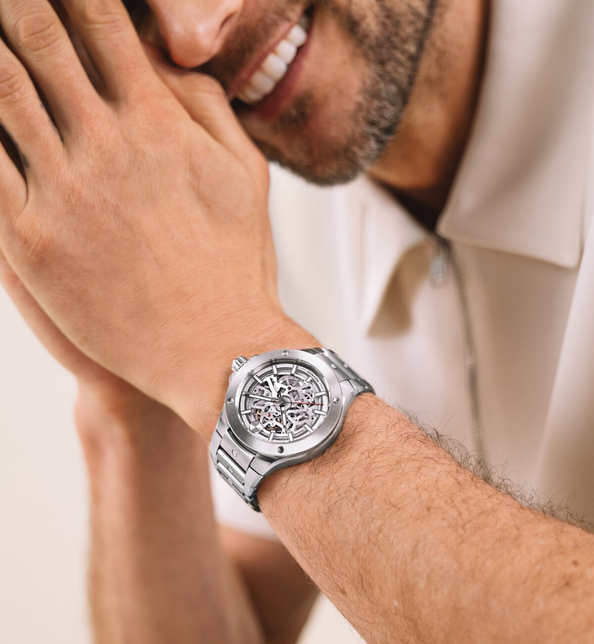 Man resting his head on his hands while wearing the Movado Alta SE silver tone bracelet watch with skeleton dial.