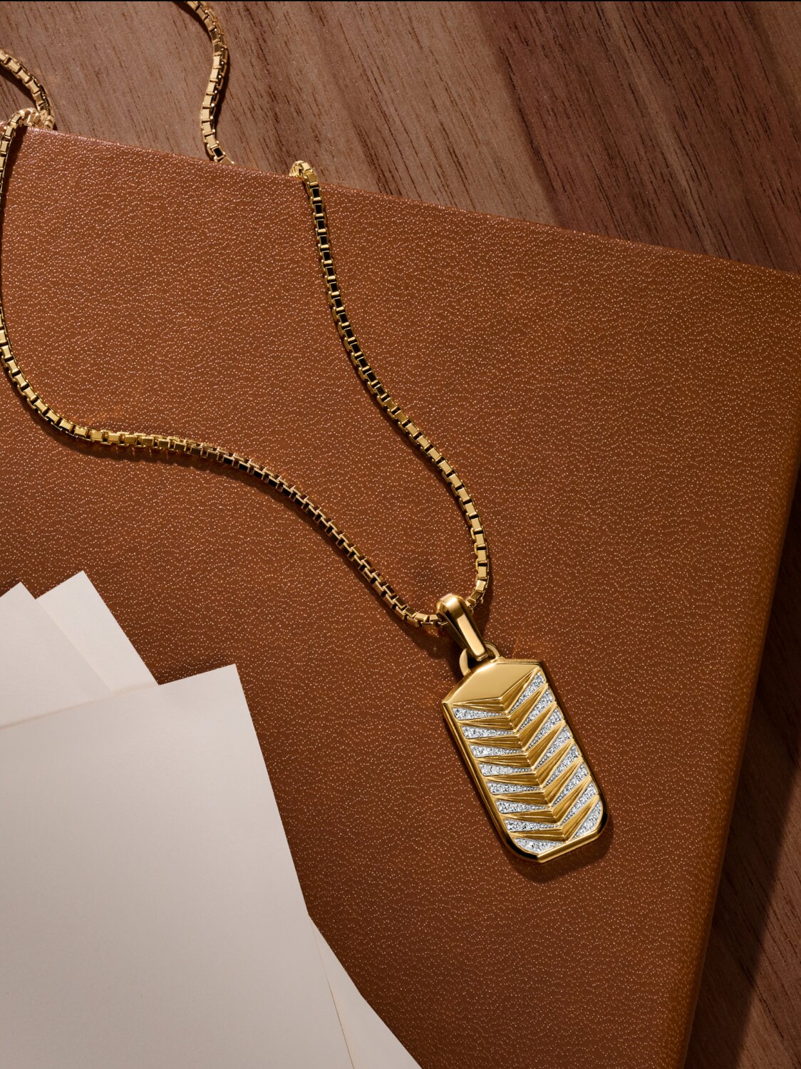 Men's M Chevron Necklace laying on a notebook