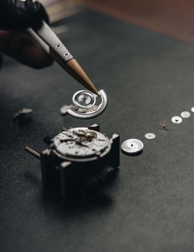 Close up of someone assembling the automatic movement with tweezers.