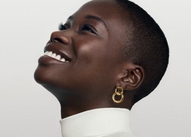 Woman smiling wearing gold tone Curve double hoop earrings.