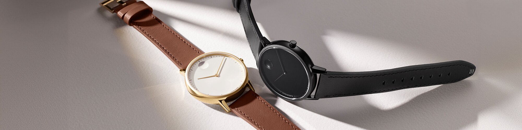 Face watch with brown strap and white dial next to a black Face watch.