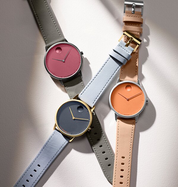 Movado Face watches with leather straps. Grey strap with pink dial, blue strap with blue dial and orange strap with orange dial