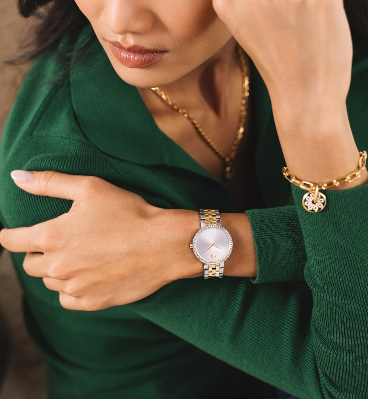 Woman in a green sweater wearing a two tone Museum Classic watch with lab grown diamonds. She is also wearing the gold tone Fleur necklace and bracelet.