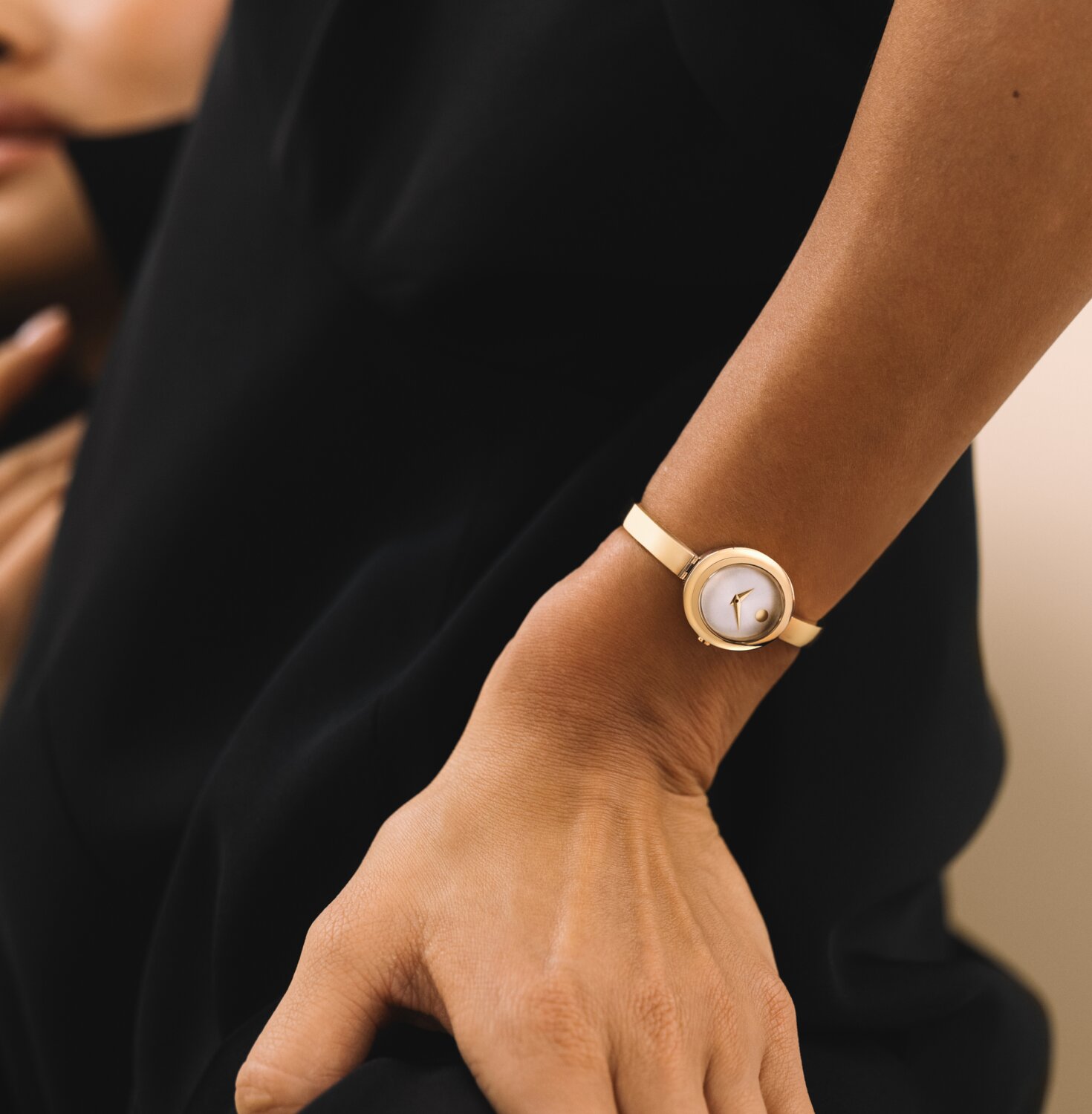 Woman wearing a Museum Bangle watch with gold tone bracelet and oval shaped white dial.