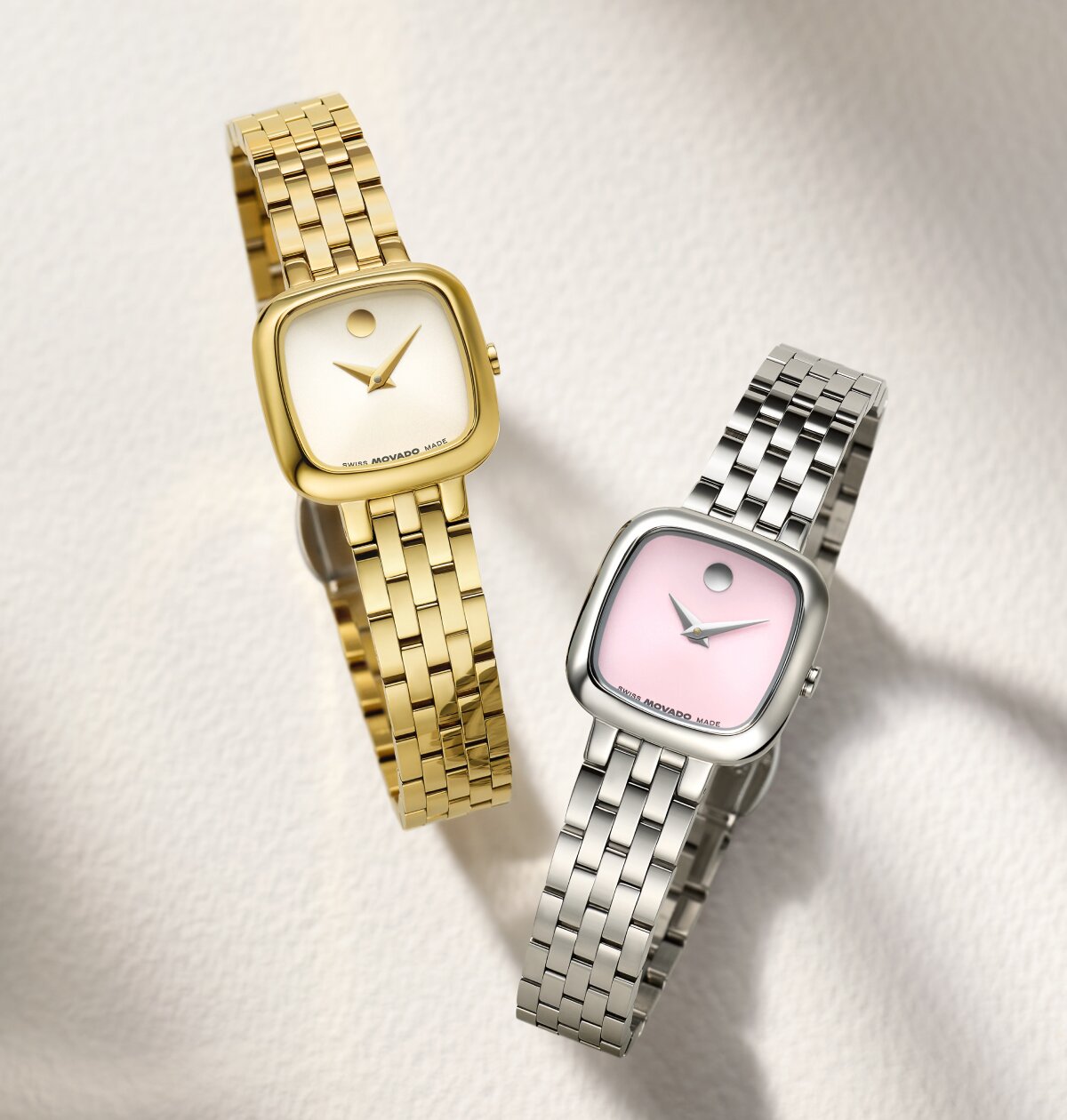 Gold Museum Classic bracelet watch with white square dial next to a stainless steel Museum Classic bracelet watch with pink square dial.