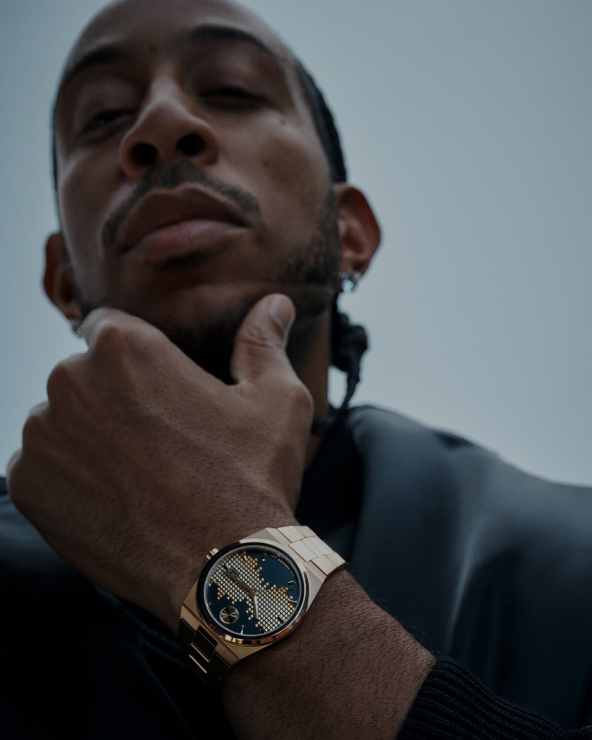 Julianne Moore in a black long sleeve top, leaning on a table, wearing the gold tone Museum Imperiale bracelet watch.
