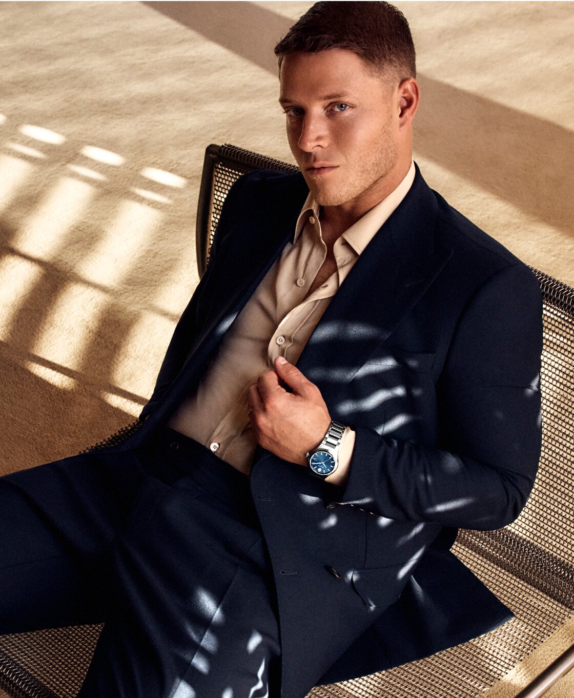 Christian McCaffrey sitting in a chair, wearing a suit and the Museum Imperial watch with silver bracelet and blue dial