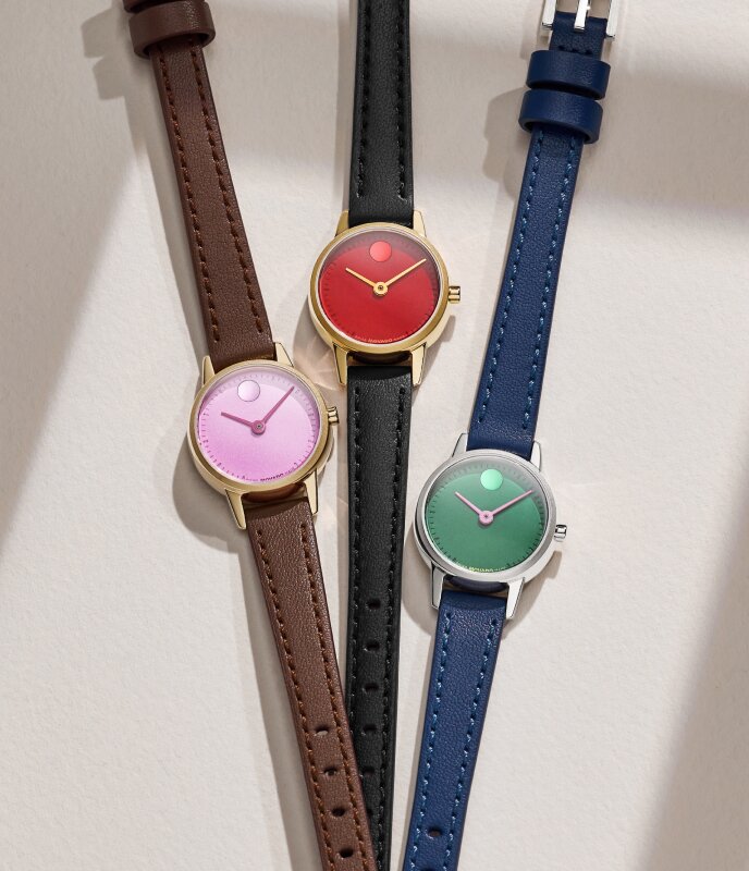 Three Baby Face leather watches in brown strap with pink dial, black strap with red dial and blue strap with green dial.