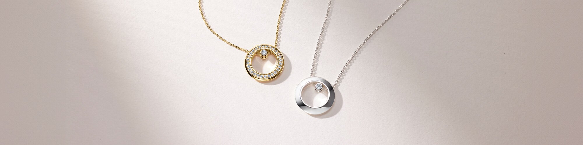 Gold tone Ono necklace with lab grown diamonds next to a silver Ono necklace with one lab grown diamond. 