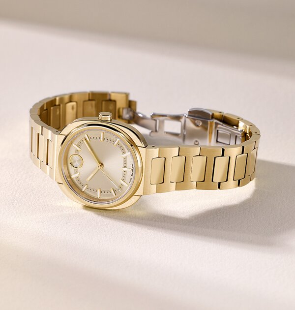 Gold tone BOLD Nuvo bracelet watch with square dial laying on its side.