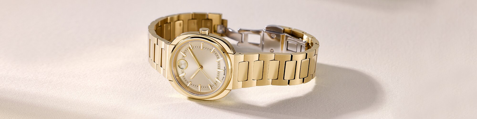 Gold tone BOLD Nuvo bracelet watch with square dial laying on its side.