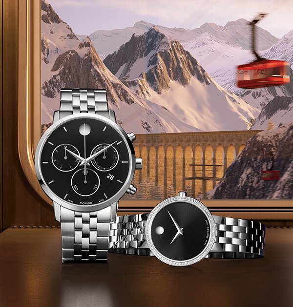 Silver watch with black chronograph dial standing next to a women's silver watch with black dial that is laying down