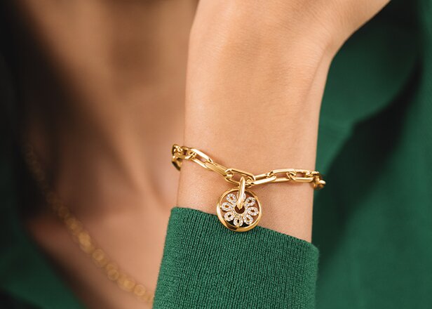 Gold tone bracelet with fleur charm on a women's wrist