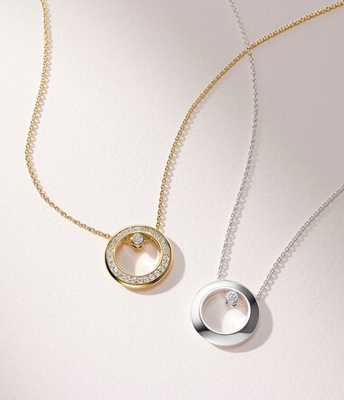 Gold plated Ono necklace with lab grown diamonds next to a silver Ono necklace with one lab grown diamond. 