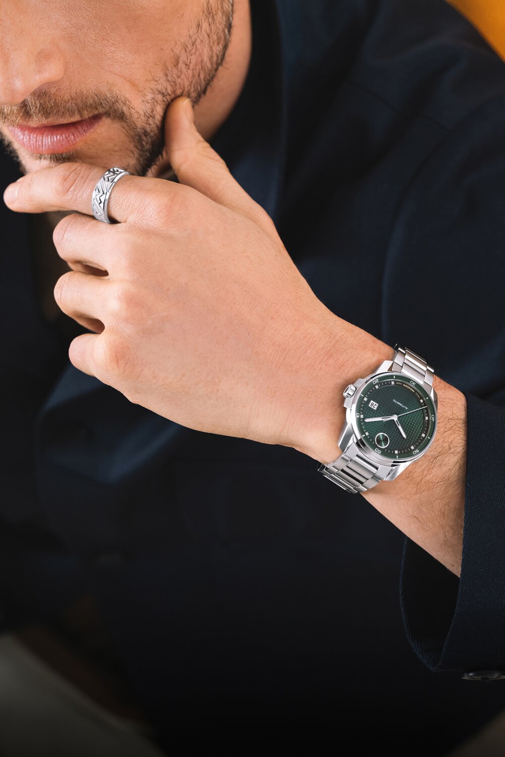 Man in a black sweater wearing the BOLD Verso Automatic watch with stainless steel bracelet and green dial.