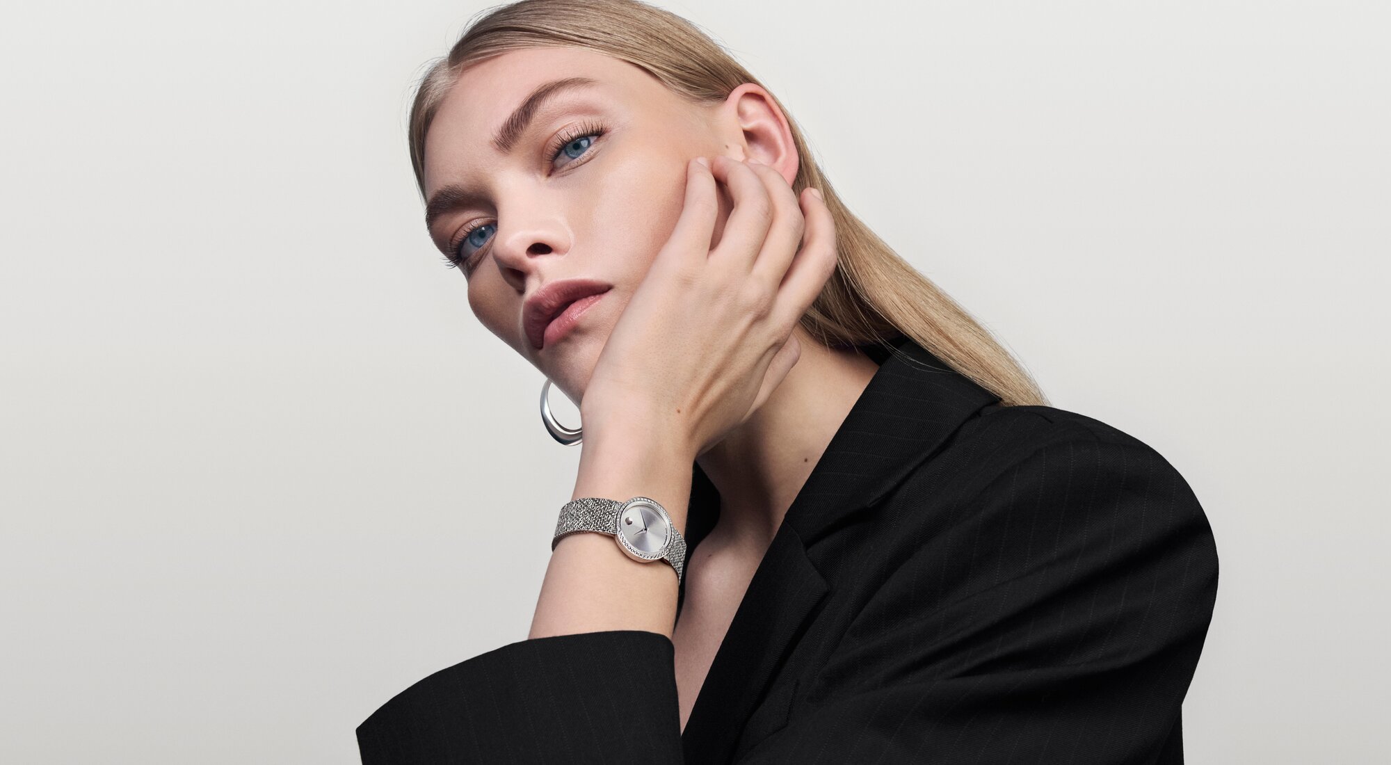 Woman in a black blazer wearing the stainless steel Museum Velura watch with mesh bracelet and lab grown diamond bezel.