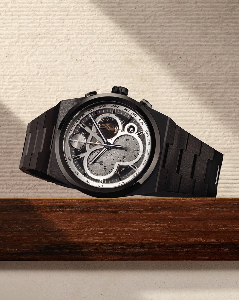Black BOLD Quest Skeleton bracelet watch laying on its side on a wooden ledge in front of a tan background