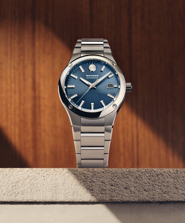 Museum Imperiale watch with silver bracelet and blue dial sitting on a stone ledge in front of a wooden wall