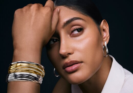 Woman wearing the Curve bangles in gold tone and silver.