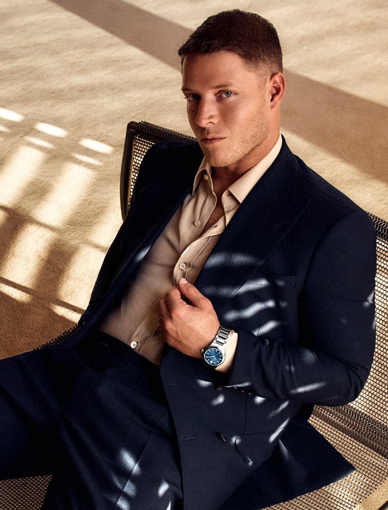 Christian McCaffrey sitting down in a suit wearing a Museum Imperiale watch with blue dial and silver bracelet.