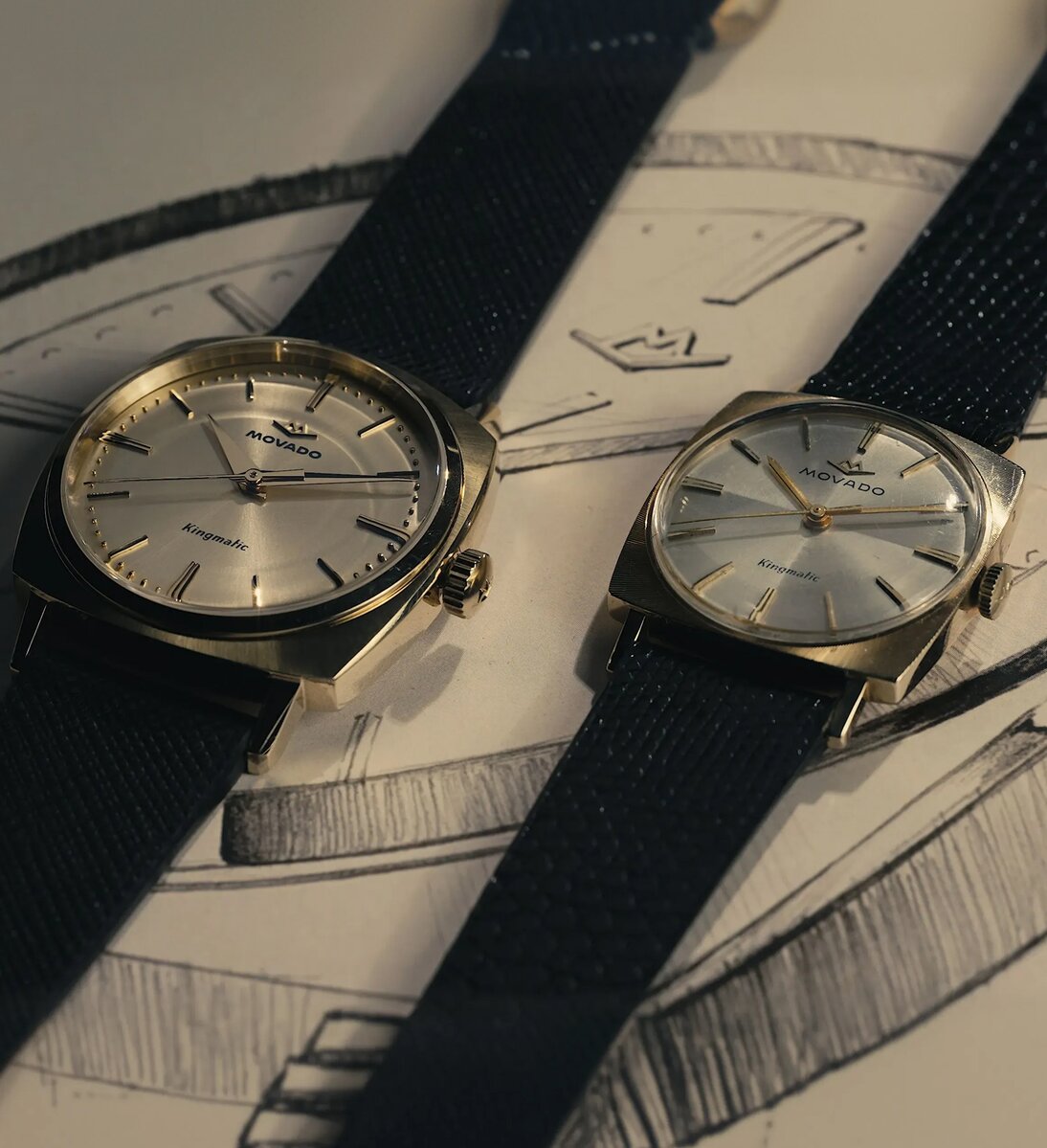 Original Heritage Kingmatic watch with black strap and gold square dial laying next to the new Heritage Kingmatic watch in the same color.
