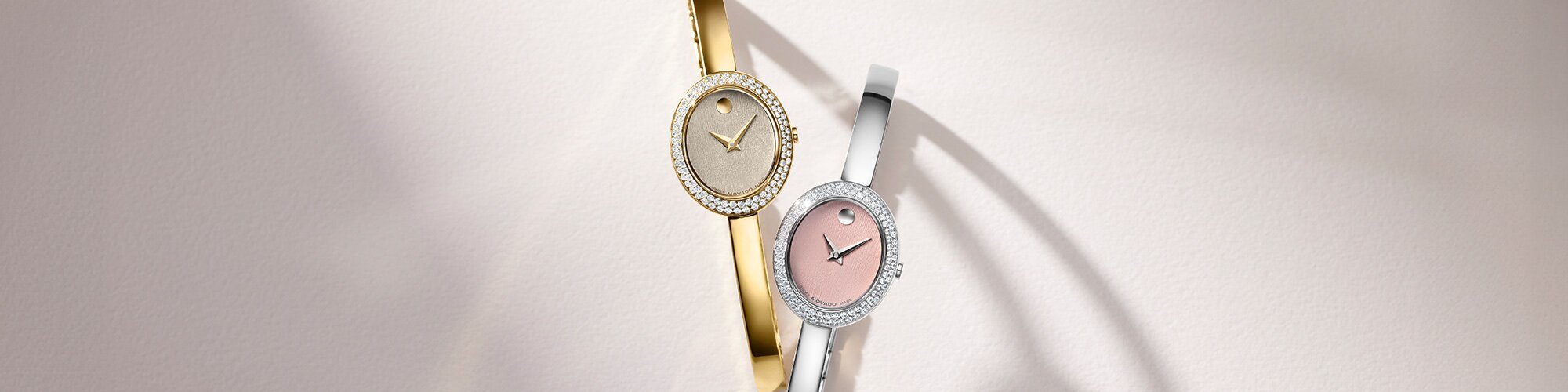 Gold tone Museum Bangle watch with lab grown diamond bezel next to silver bangle watch with pink dial and lab grown diamond bezel.