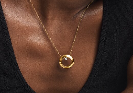 Woman wearing the gold tone Ono necklace with lab grown diamond.