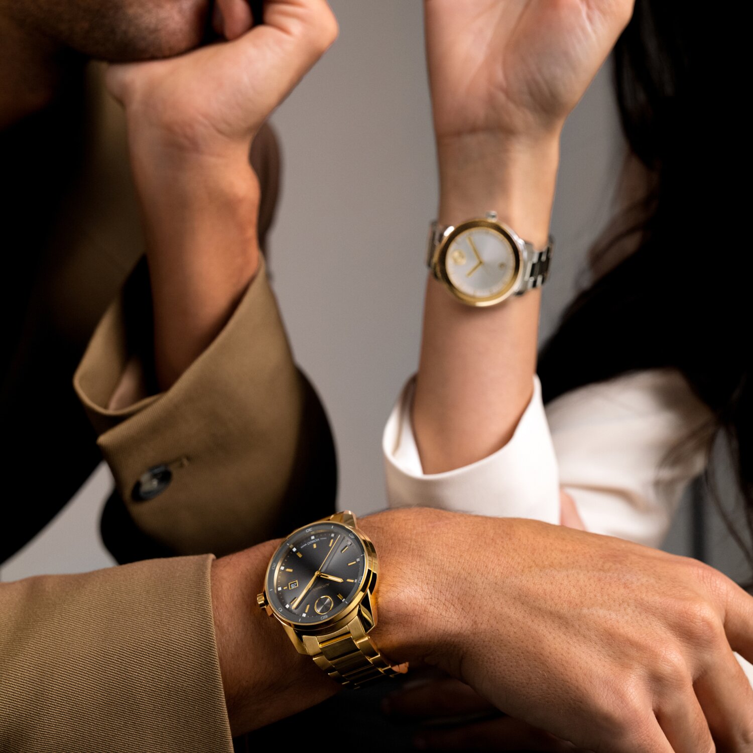 Movado BOLD Verso watch with gold bracelet and grey dial worn on a man and a Movado BOLD Verso two toned watch worn on a woman.