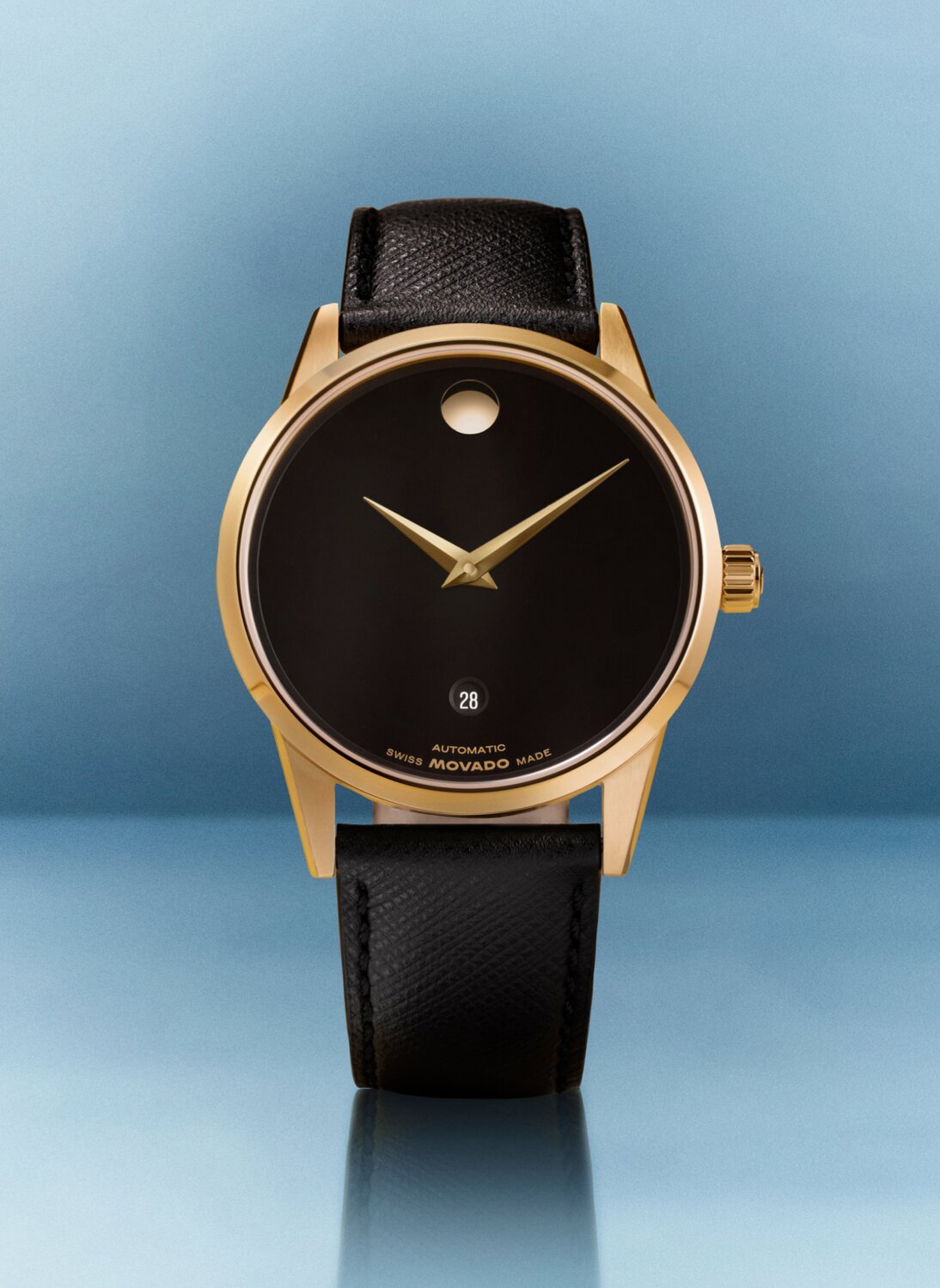 Museum Classic Automatic watch with black leather strap and black dial with gold tone accents in front of a blue background.