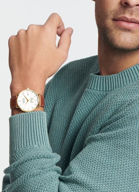 Man in a blue sweater wearing a Heritage Silhouette watch with brown strap and white dial.