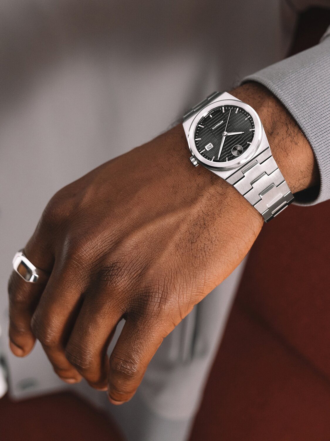 Man in a grey jacket wearing a BOLD Quest Automatic watch with stainless steel bracelet and black dial.