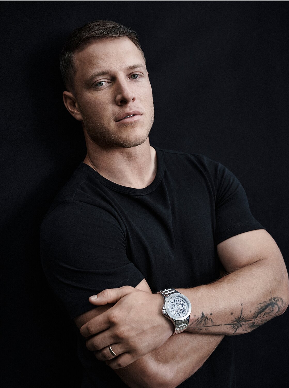 Christian McCaffrey wearing a black shirt with his arms crossed wearing the silver tone Alta SE watch with Skeleton dial.