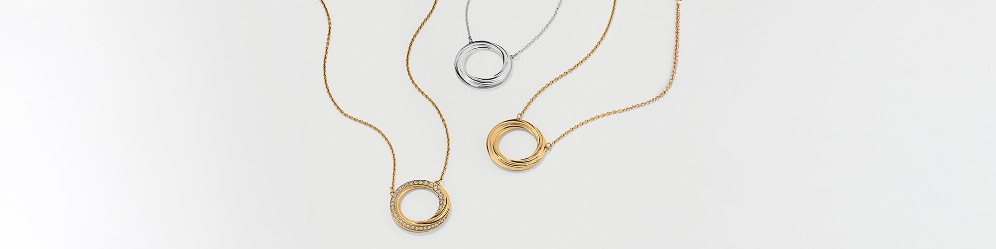 Gold tone necklace with fleur charm next to silver fleur charm necklace
