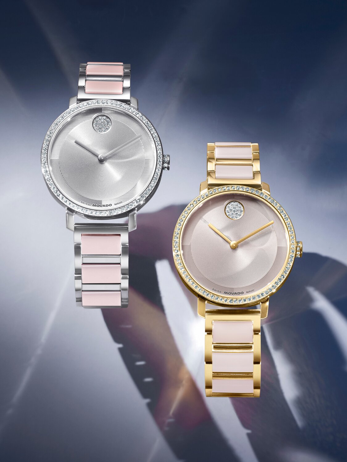 Stainless steel BOLD Evolution 2.0 bracelet watch with pink ceramic center links and crystal bezel. The gold tone Evolution 2.0 bracelet watch with taupe center links and crystal bezel is next to it. 