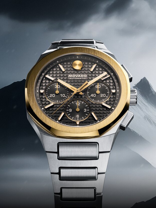 Two Tone Alta Centurion bracelet watch with 18K Gold Bezel in front of mountains.